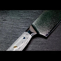 Detailansicht des Messerkropfs am Übergang zwischen Damastklinge und weißem Howlith-Mineralgriff
